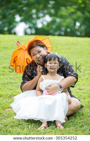 Little asian girl playing on green grass with her mother in the park,Bangkok Thailand