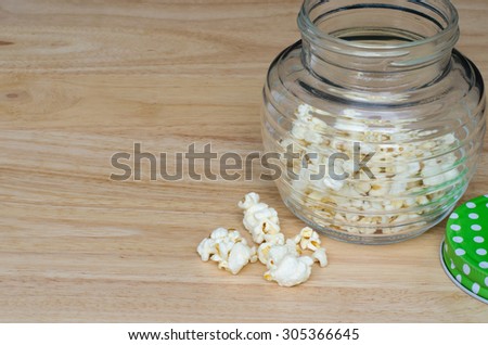 A jar of popcorn on a wooden table