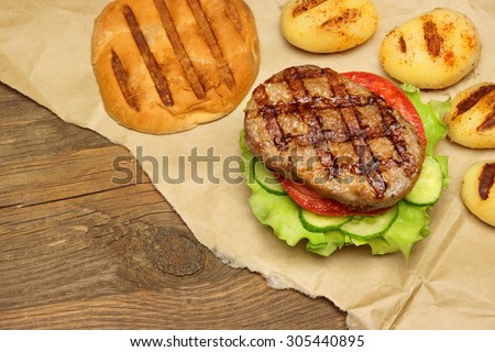 Close-up Top View Of Grilled Homemade Hamburger On The Brown Paper, Old Rough Wooden Rustic Table In The Background. Meal Concept