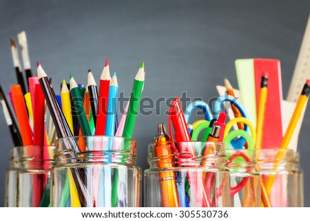 School supplies in jars against the blackboard