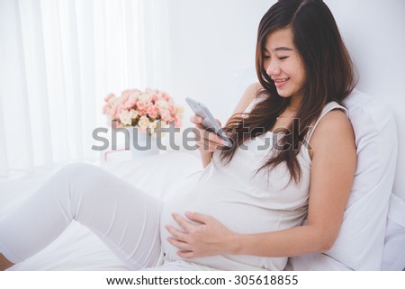 A portrait of a beautiful asian pregnant woman using a smartphone