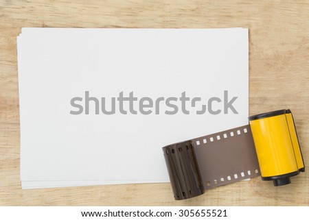 Blank paper with photo film in cartridge  on wooden table.