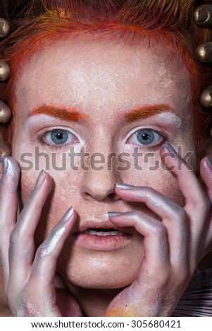 Art picture of a girl with creative make-up, textured leather, red-orange tones on a black background
