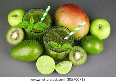 Green healthy juice with fruits and mint on gray background