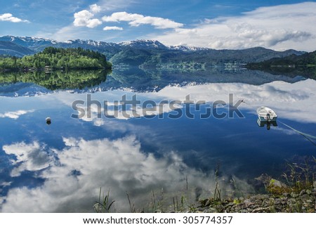 Boat on a Fjord Bay in Norway:  A small white boat sits under blue skies on a fjord in southwest Norway.
