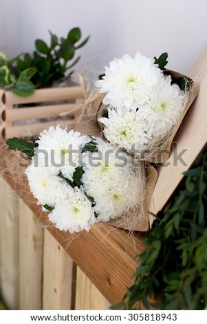 Two bouquets of white chrysanthemums in a paper cornet