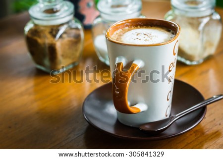 Coffee cup placed on a wooden table, vintage style photo.
