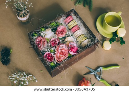 Preparation of flower box with macaroons, top view of florist workplace
