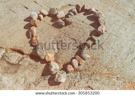 Stones in a heart shaped love sign on granite rock bakground. Filters applied
