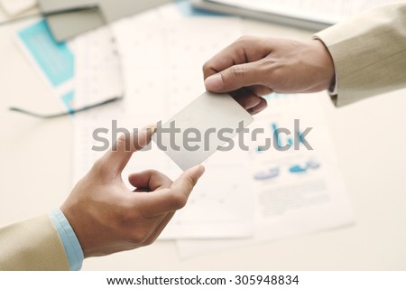 Hands of manager giving blank business card to his partner