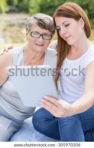 Picture of grandmother and her granddaughter using tablet during picnic