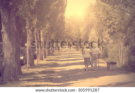 Vintage photo of old couple walking in the park a sunny day