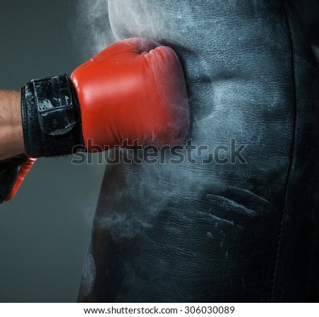 Close-up hand of boxer at the moment of impact on punching bag over black background Royalty-Free Stock Photo #306030089