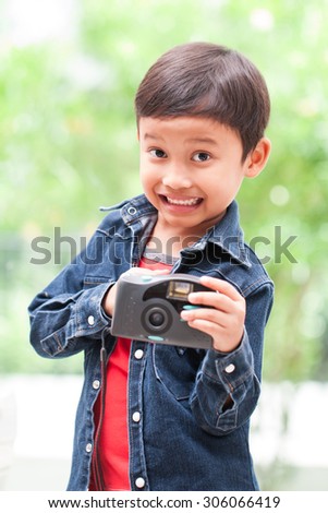 Happy asian boy with compact camera.