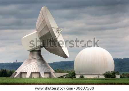 An earth station satellite installation with ancillary building - the type used for broadcasting. Poor weather. Royalty-Free Stock Photo #30607588