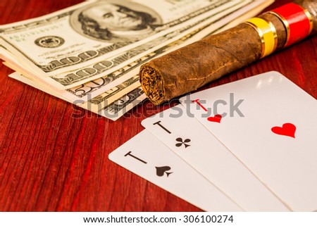 Cuban cigar with playing cards and money on the table mahogany. Focus on the cuban cigar, identification cards ace Russian letter