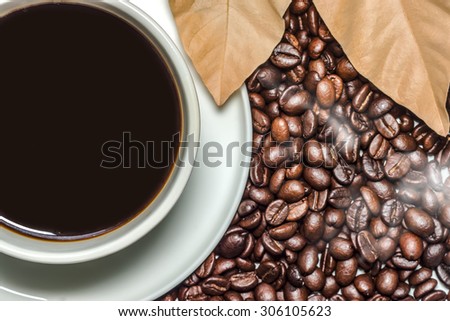 Black coffee in the cup and blur roasted coffee beans background.