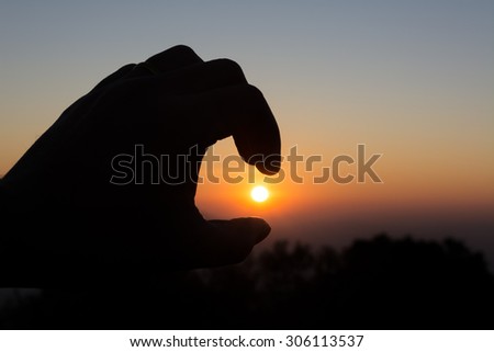 image of finger catch the sun and morning sky .