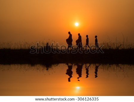 Silhouette of monk walk on the field  , Thailand Royalty-Free Stock Photo #306126335