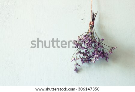 bouquet of dried flowers hanging on rope against wooden background