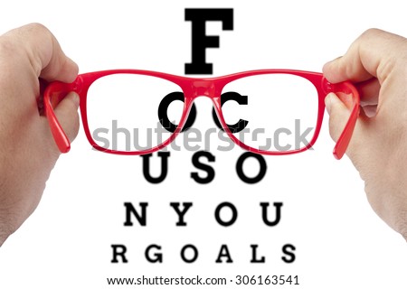 Red spectacles focusing on text focus on your goals arranged as eye chart test