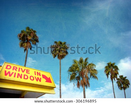 aged and worn vintage photo of drive in window sign and palm trees                               