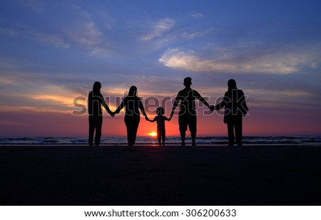 Silhouette happy family standing on the beach on the dawn time.
Concept of friendly family. 
(Shallow DOF, slight motion blur)