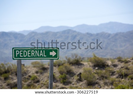 Wooden sign post showing the direction to Pedernal with the dry and arid mountains in the background. Pedernal is a famous travel destination in North of Argentina.