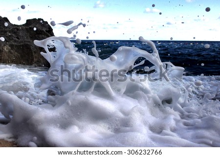 Ocean splash with a lot of foam near the dark rocks