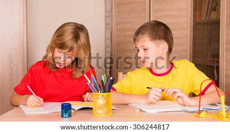 Cute children working on their homework together. Boy and girl doing homework at home. Education and help concept.