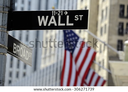 Wall street sign with focus on sign, blurred American flag background Royalty-Free Stock Photo #306271739