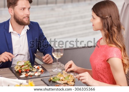 Intent glance. Beautiful couple having meal and looking at each other in restaurant.