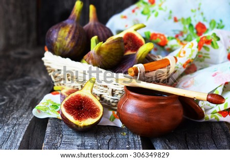 Ripe figs in the little basket  with honey in little ceramic bowl on the old wooden table