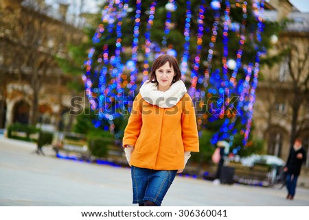 Happy young tourist in Paris on a winter day, main Parisian Christmas tree in the background