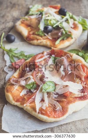 Prosciutto mini pizza with parmesan cheese on wooden background