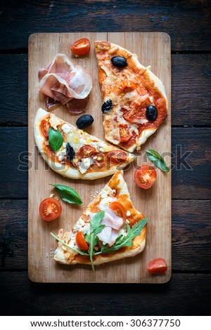 Slices of mini pizza variety served on wooden board and background,from above