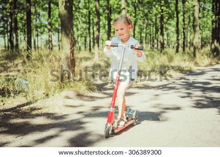 little girl riding scooter in park