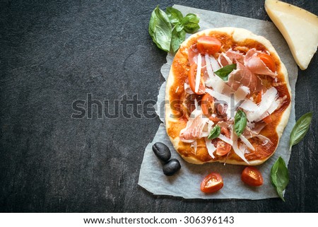 Prosciutto mini pizza on dark background with blank space for your ads 