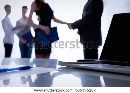 Laptop computer on desk , businesspeople standing in the background