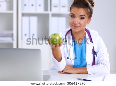 Female doctor hand holding a green apple, sitting .