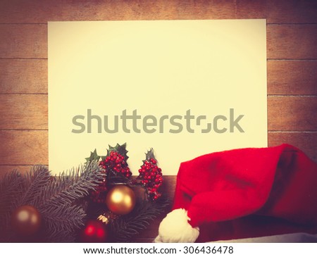 White papaer and christmas toys with Santas hat on wooden background.