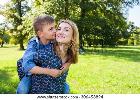 Son hugging kissing young mother in the park