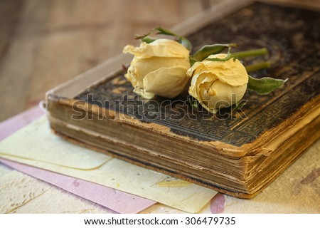 selective focus image of dry rose and old vintage books on wooden table. retro filtered image