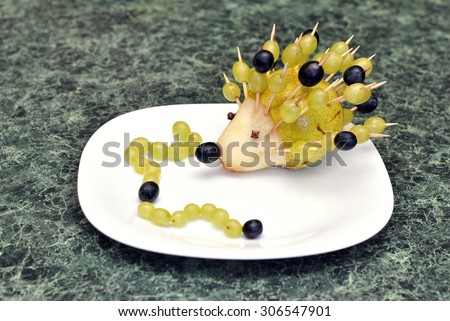 Funny figure hedgehog and caterpillars of fruit for children food, made by a child's hand