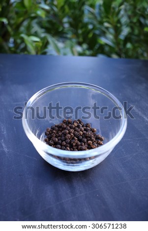 Black pepper in bowl on black background