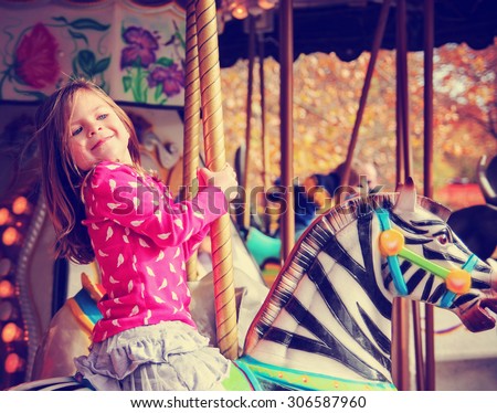  a young girl riding on a merry go round at the zoo toned with a retro vintage instagram filter effect app or action Royalty-Free Stock Photo #306587960