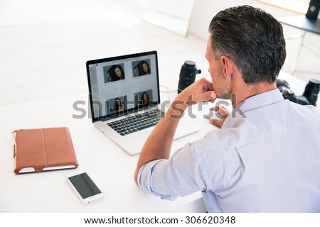 Back view portrait of a young man using laptop at his workplace