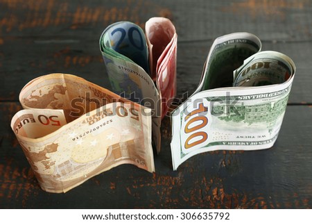 Money in form of hearts on rustic wooden background