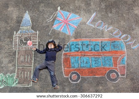 Happy little kid boy in british policeman uniform having fun with London picture drawing with colorful chalks. With Big Ben, Union Jack and red bus.