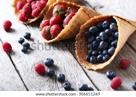 Waffle cones with berries on wooden table